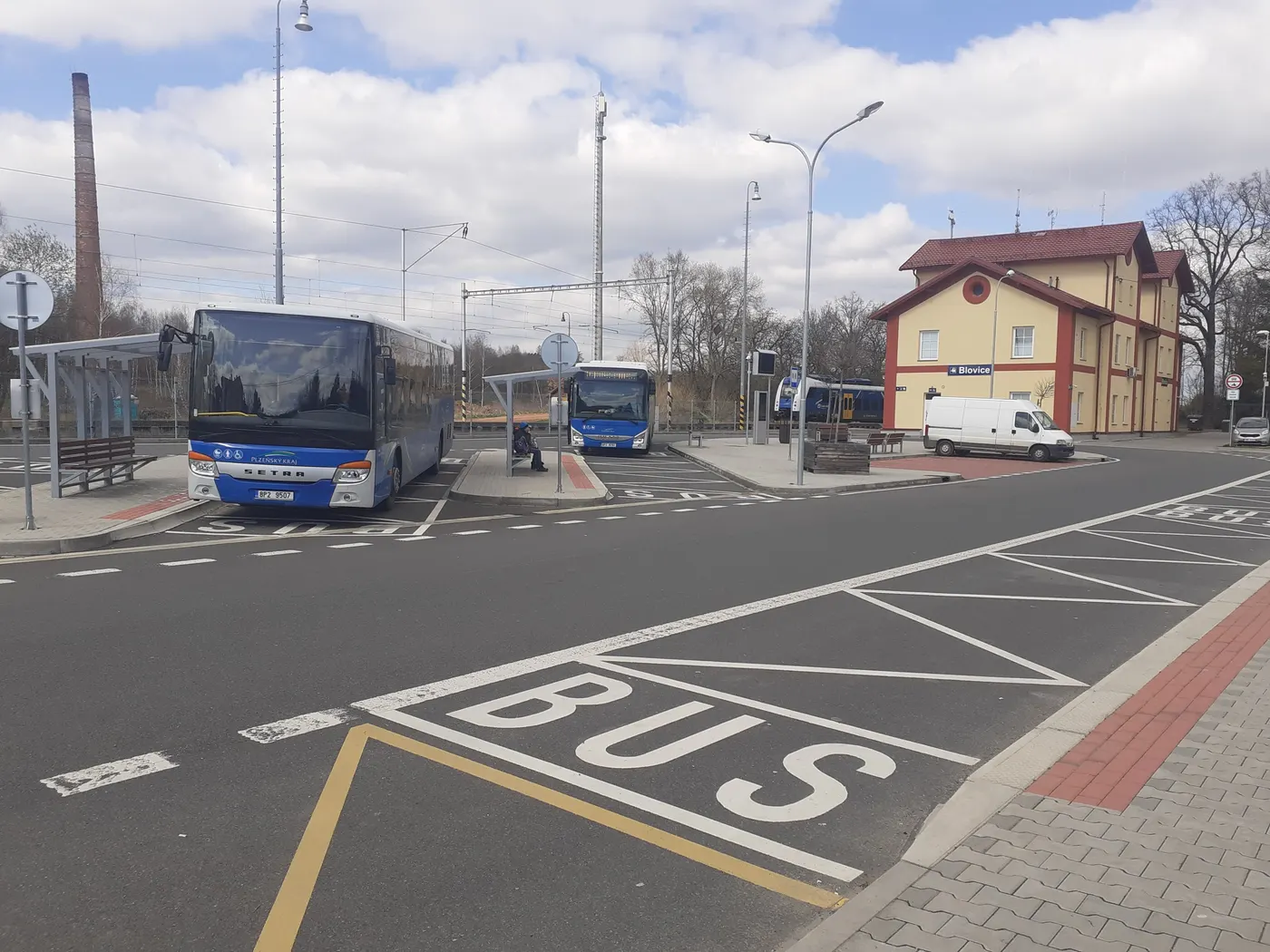 Autobusy u nádraží v Blovicích, za nimi vlak na nástupišti